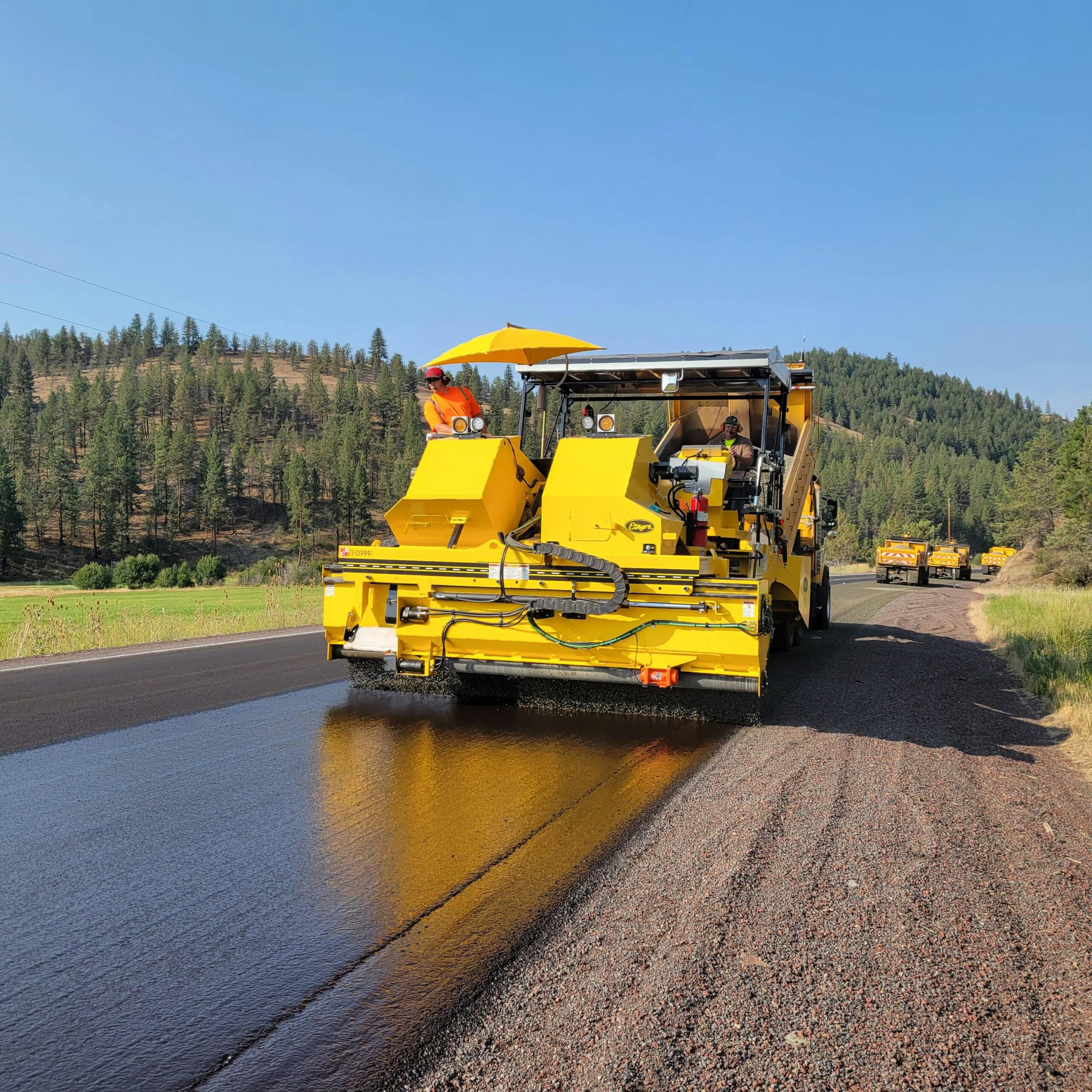 Yellow tractor working on the road laying asphalt reflecting our seal coating Colorado Springs services.