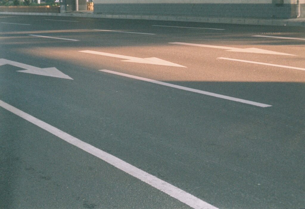 Photograph of a city street showing directional arrows on asphalt in sunlight reflecting our asphalt installation construction services.